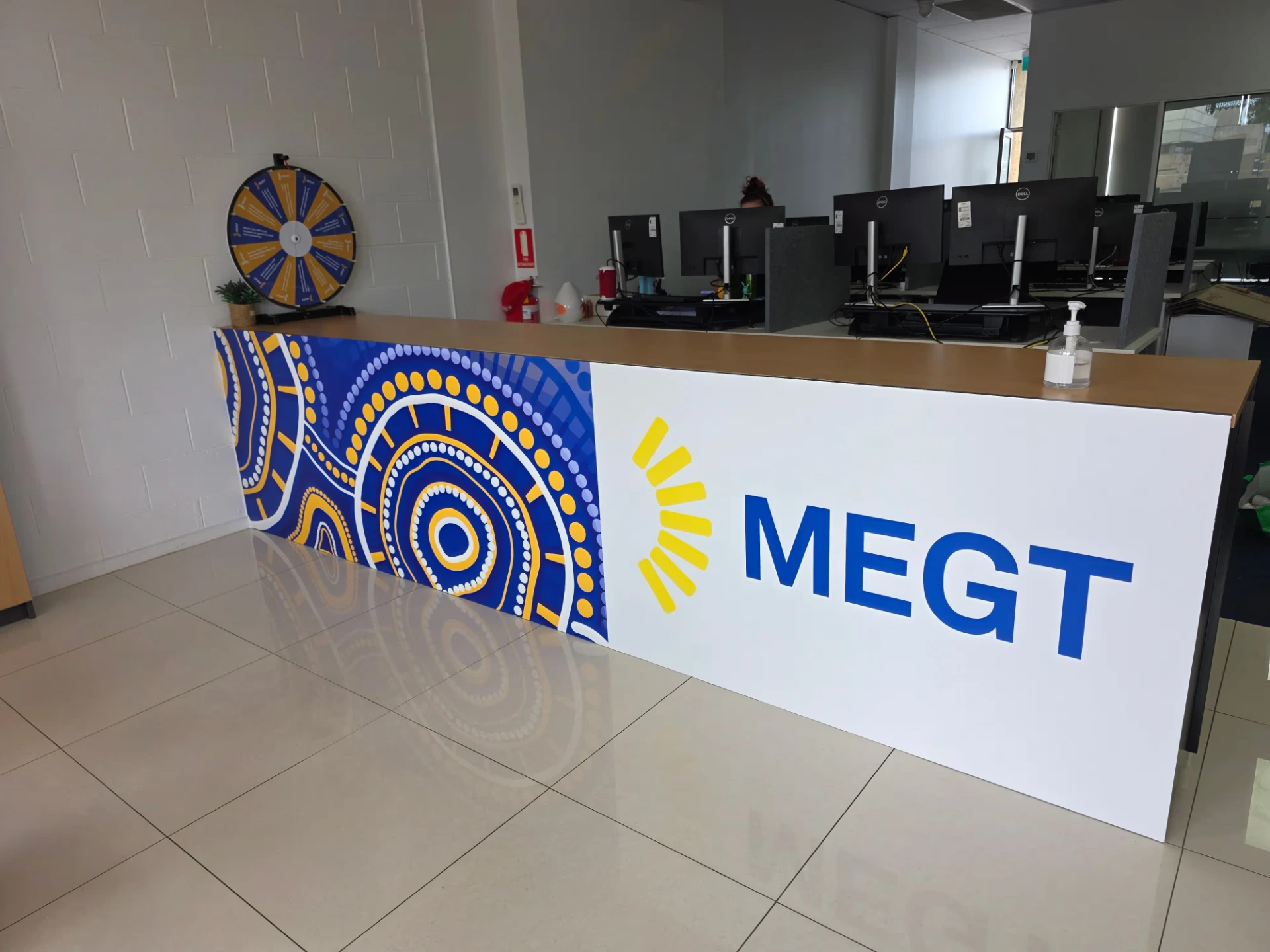 Printed reception counter graphic with large blue logo lettering and Indigenous artwork panels